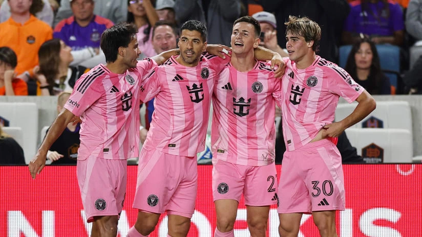 Pemain sepak bola mengenakan jersey warna pink sedang berbaris di lapangan